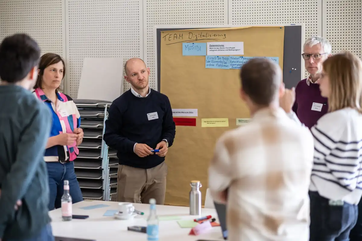 André Nitze erarbeitet mit Projektpartnern an einer Moderationswand gemeinsame Schritte zur Digitalisierung